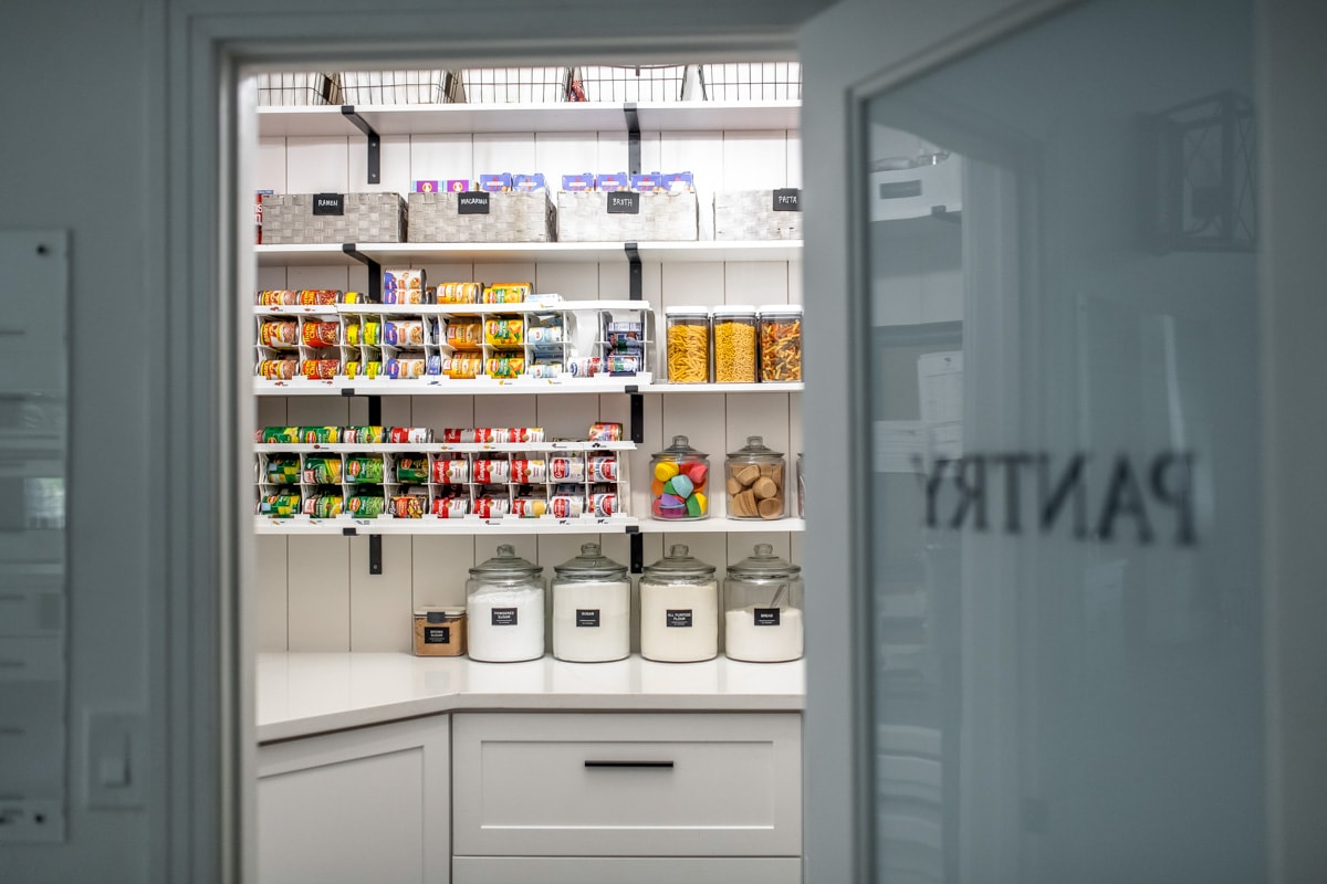 Looking inside a pantry at the food stored on the pantry shelves.