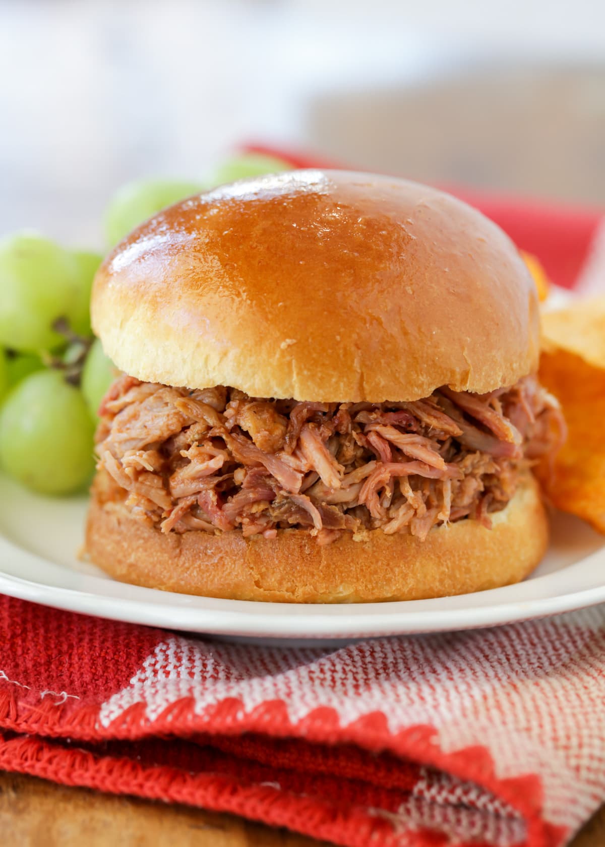 Pulled pork recipe served on a bun with grapes.