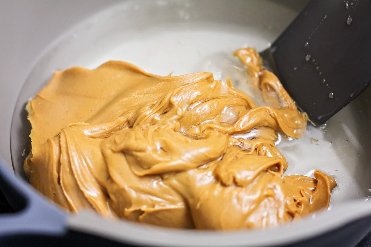 Adding peanut butter to the bowl to make scotcheroos.