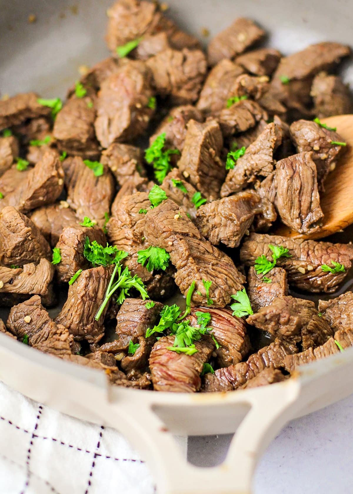 Close up of cooked steak bites seasoned with fresh herbs.