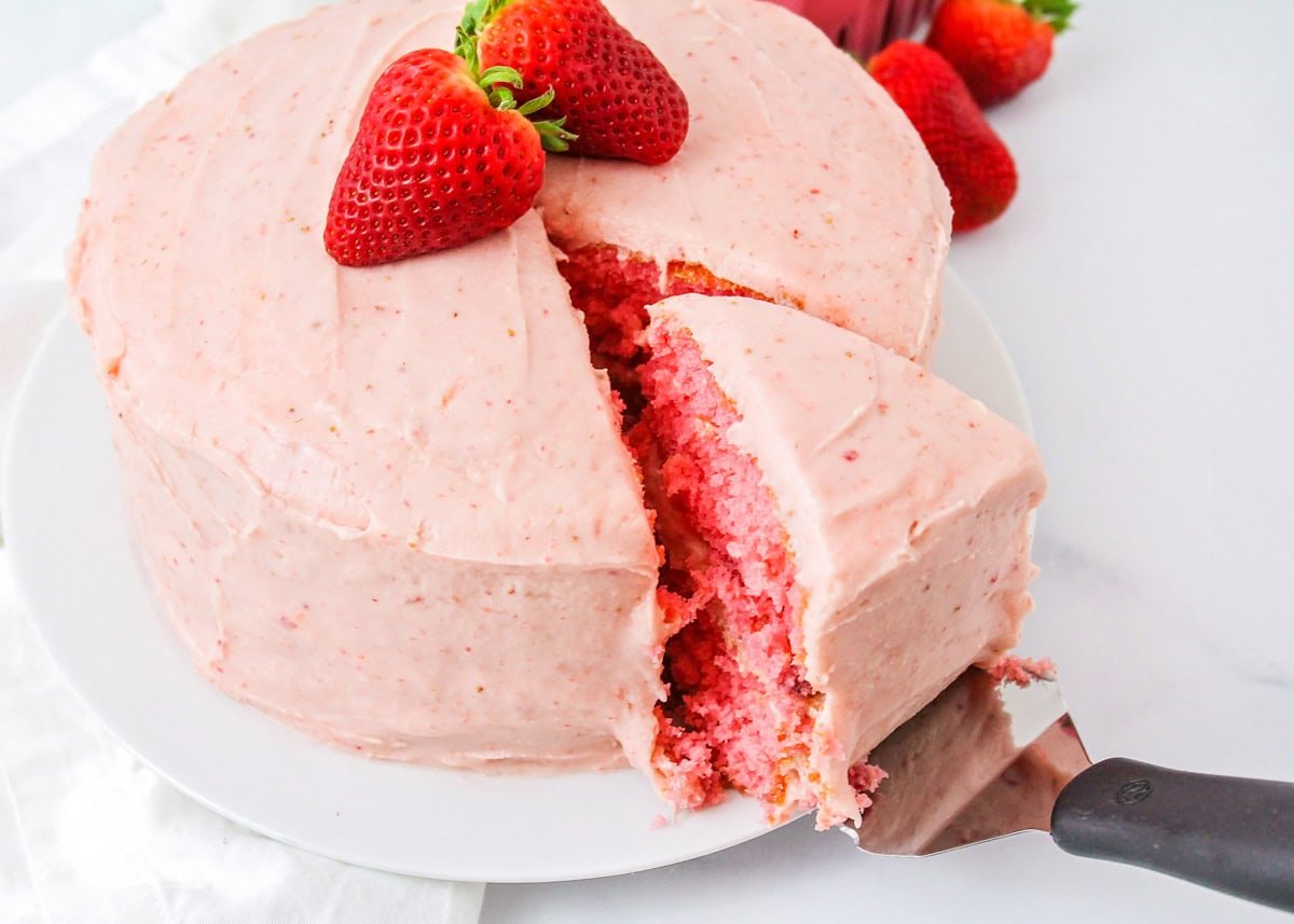 Removing a slice from a fresh homemade strawberry cake.