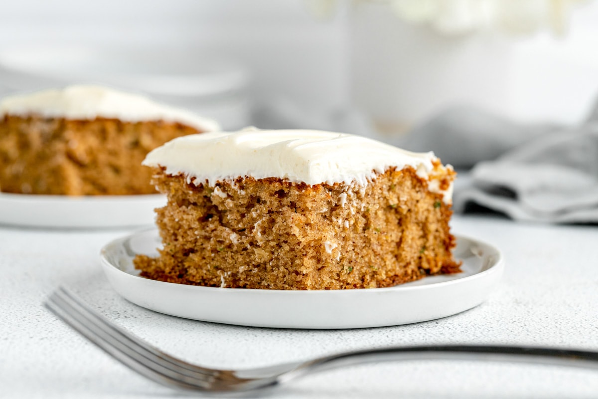 A square slice of zucchini cake is topped with cream cheese frosting.