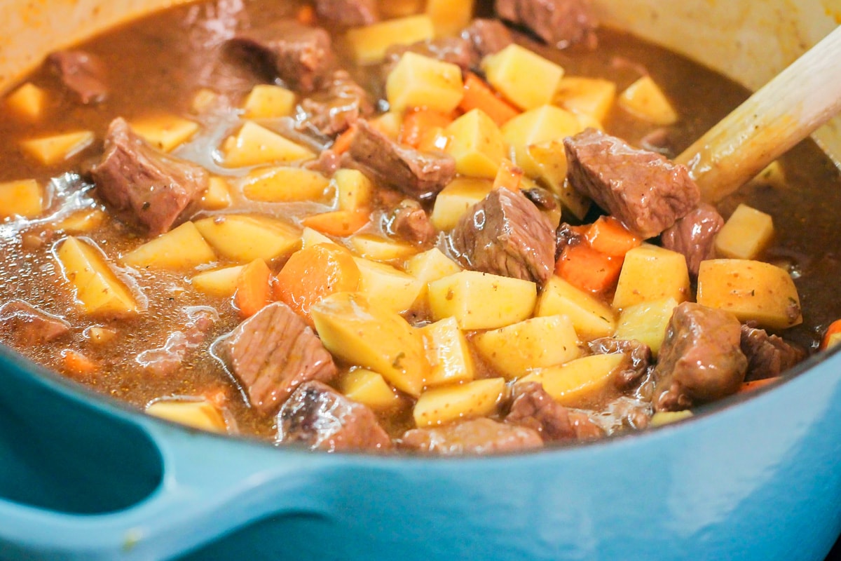 Cubes of carrots and potatoes in a beef broth in a Dutch oven.