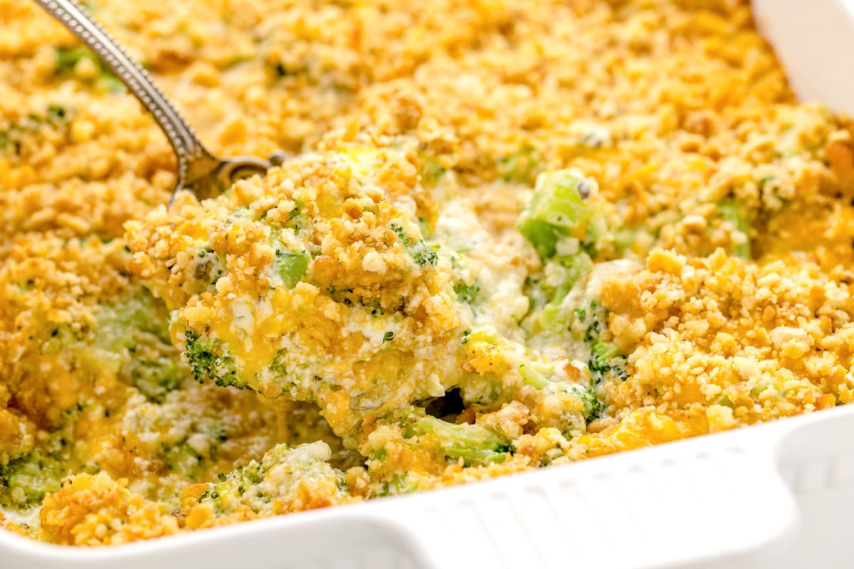 Close up of a scoop being pulled from broccoli cheese casserole.