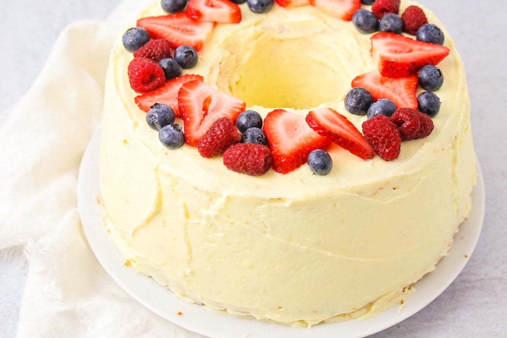 Easy chiffon cake recipe topped with orange frosting and fresh berries.