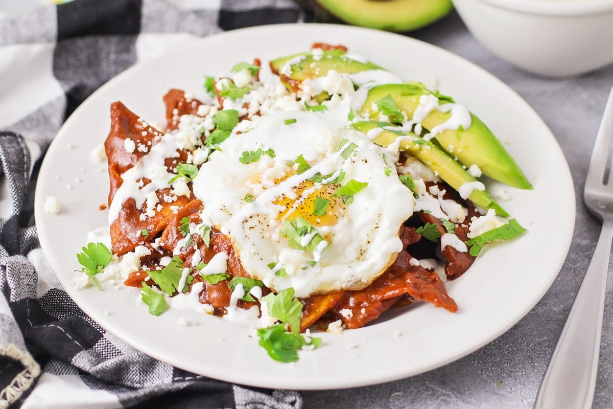 A plate of chilaquiles topped with a fried egg, avocado, and cotija.