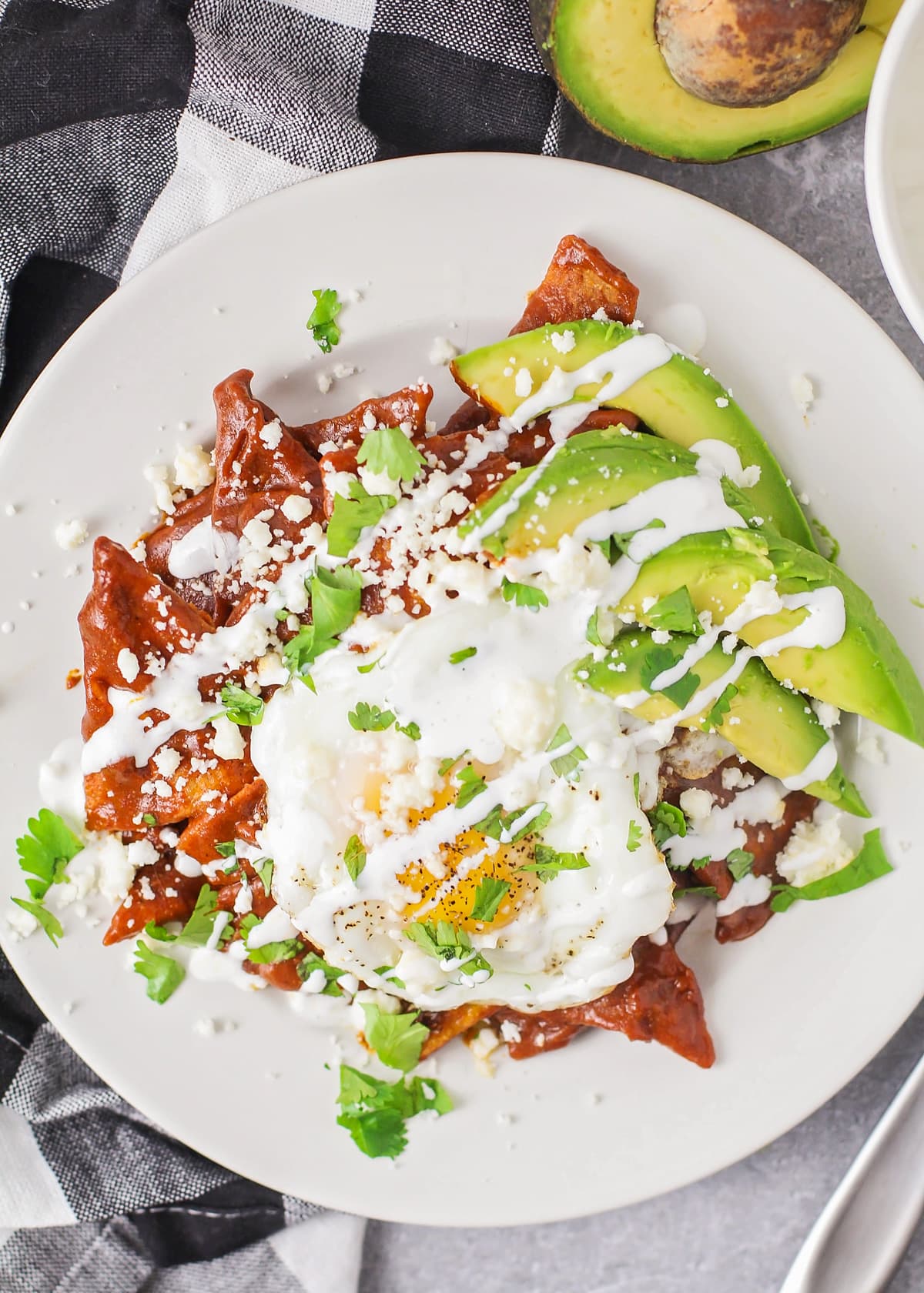Chilaquiles topped with a fried egg, avocado slices, and cotija cheese.