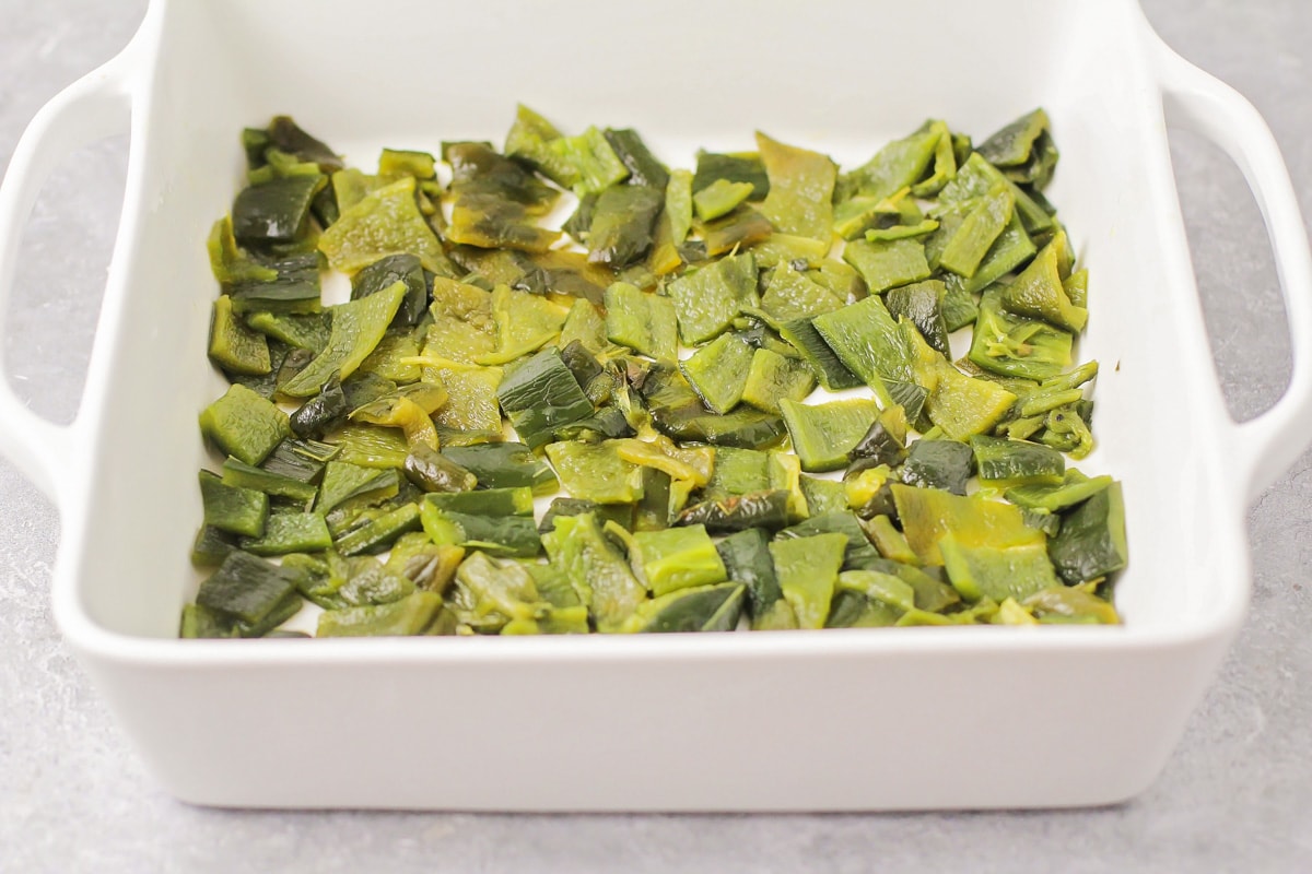 Diced roasted poblano peppers layered on the bottom of a casserole dish.