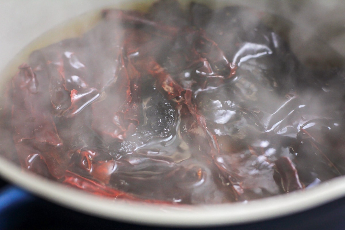 Boiling toasted peppers in a pot of water.