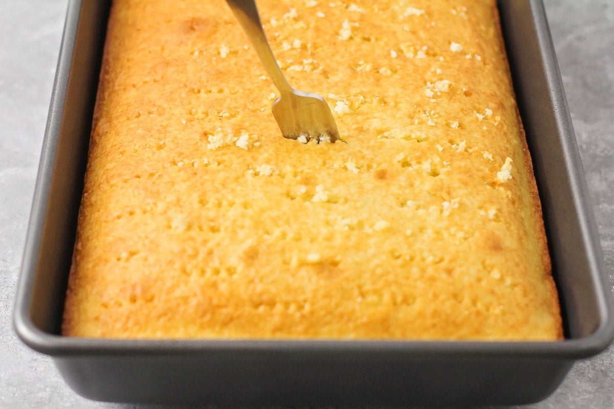 Poking holes in a baked cake.