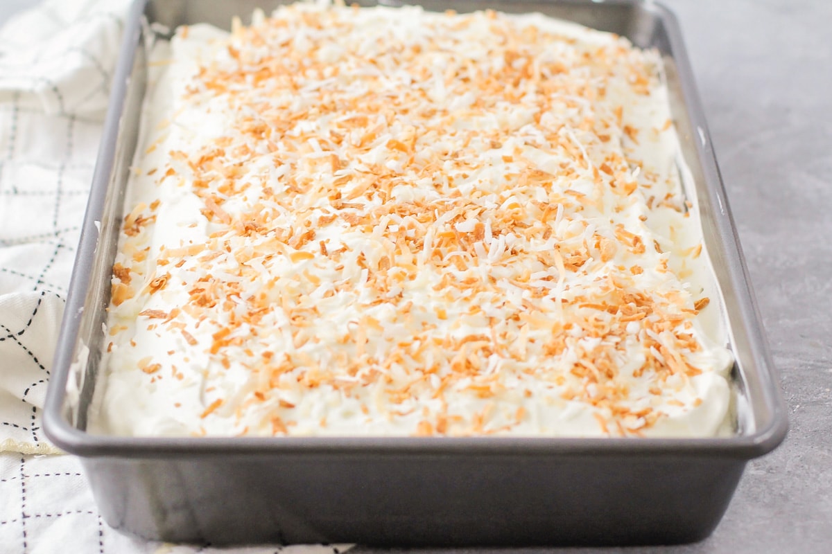 A frosted cake topped with toasted coconut.