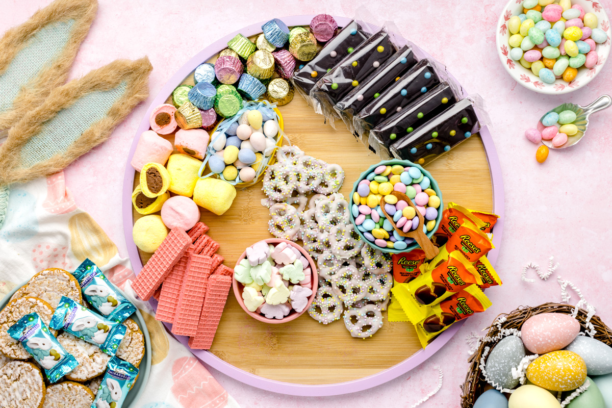 Easter candy and treats surrounding the bowls on a wooden platter.