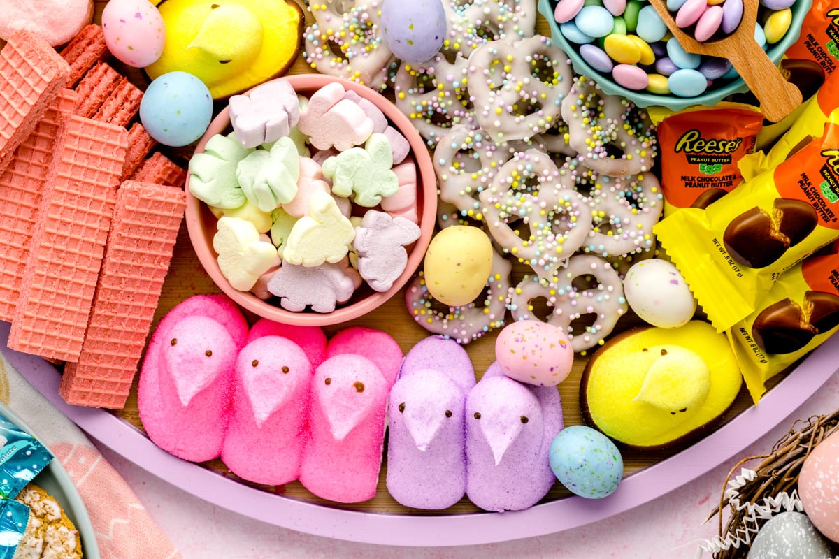 Close up of peeps, pretzels, reese's, and other Easter candy on a wooden board.