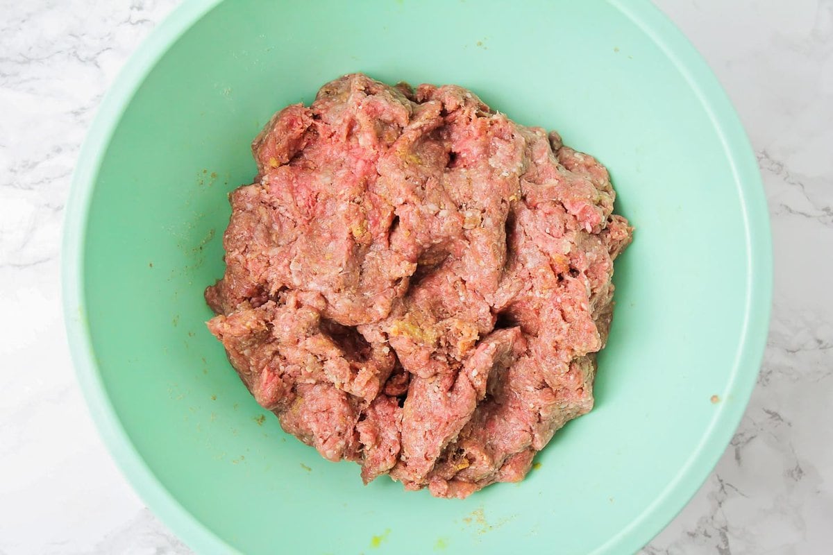 Meat and ingredients mixed in a bowl.