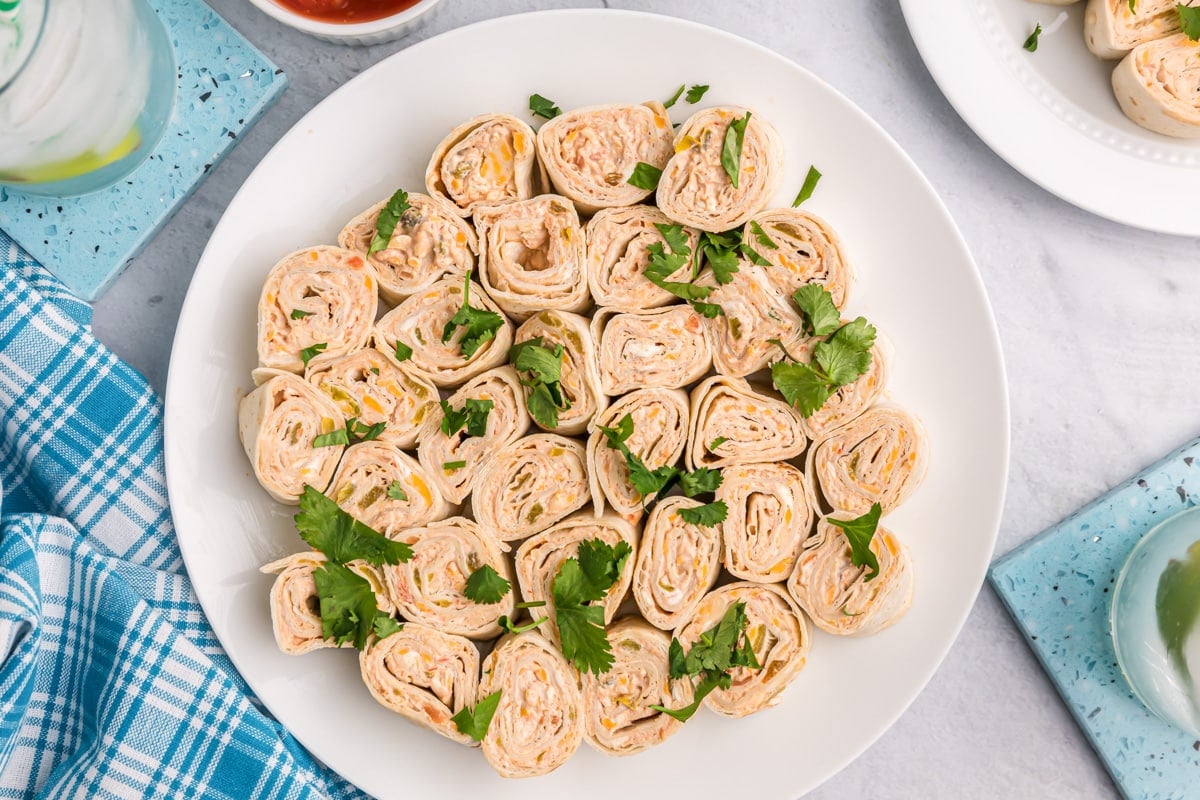 A plate of sliced pinwheels garnished with cilantro.
