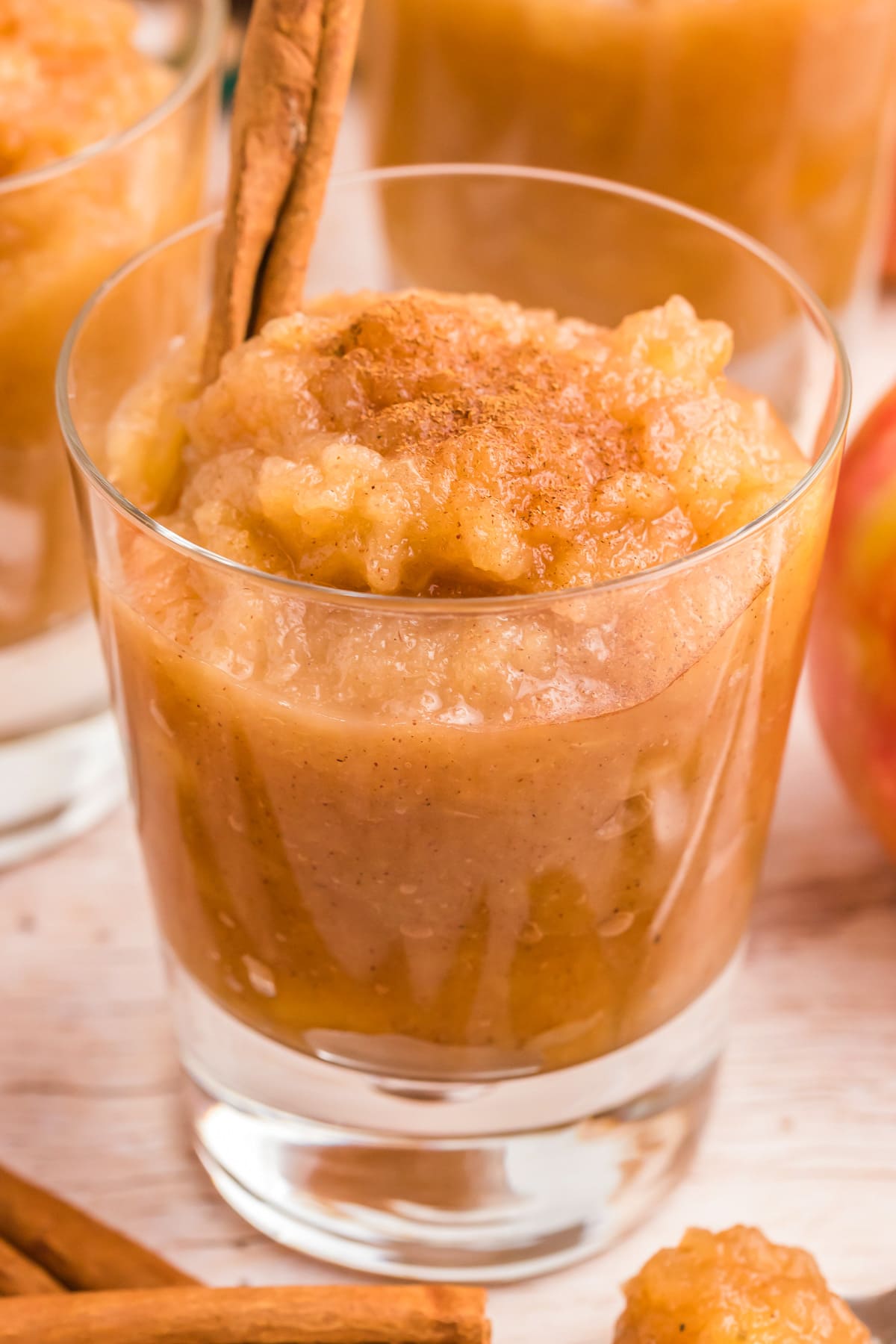 A glass filled with applesauce and topped with cinnamon.