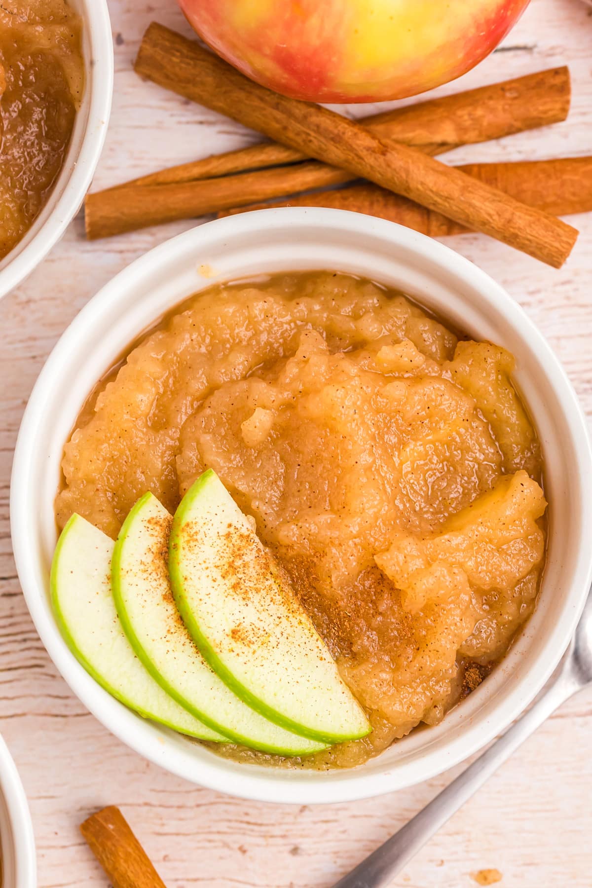 A white bowl filled with homemade applesauce and topped with cinnamon.