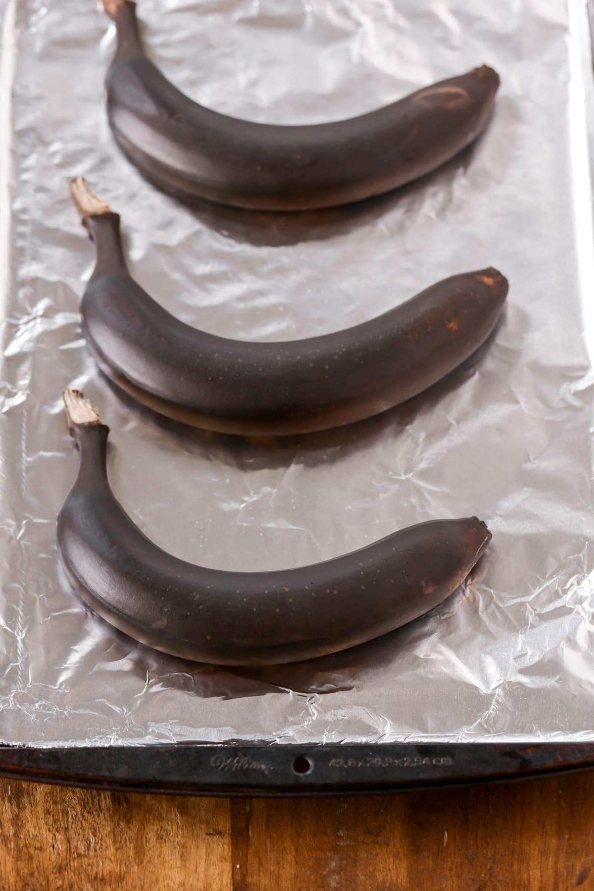 Very ripe bananas on a lined baking sheet.