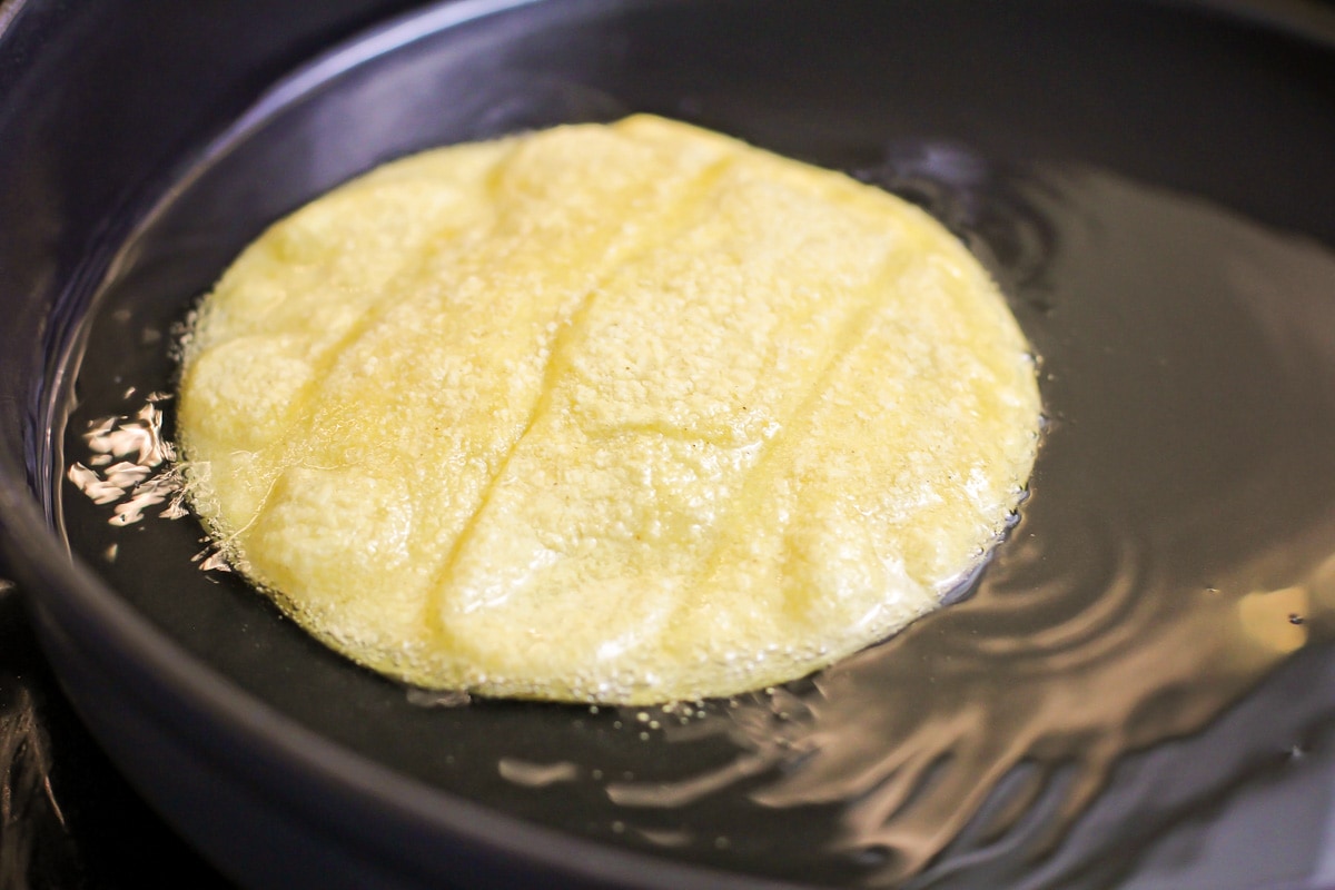Frying corn tortillas in a pan of oil.