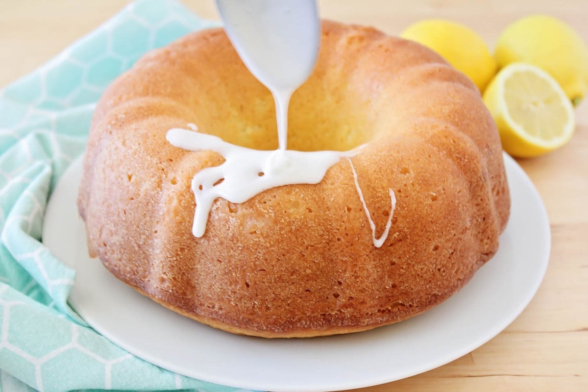 Glaze being drizzled on lemon pound cake.