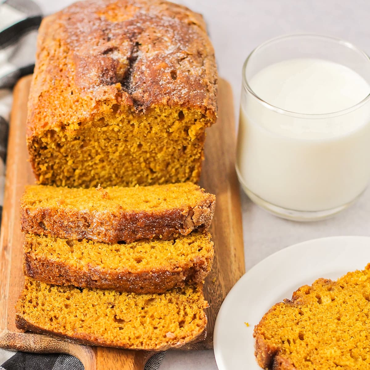 Sliced loaf of pumpkin bread recipe served with a glass of cold milk.