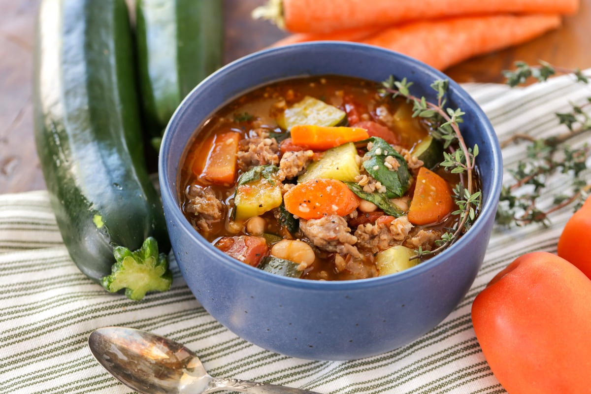 Italian sausage soup served in a blue bowl.