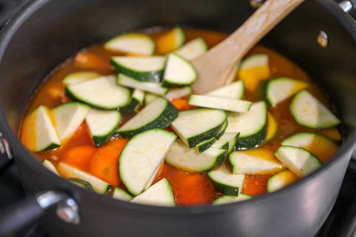 Sliced veggies in a pot of broth on the stove.