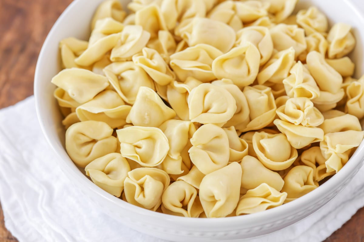 A white bowl filled with tortellini pasta.