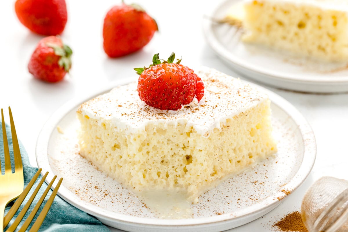 A slice of easy tres leches cake recipe on a white plate.