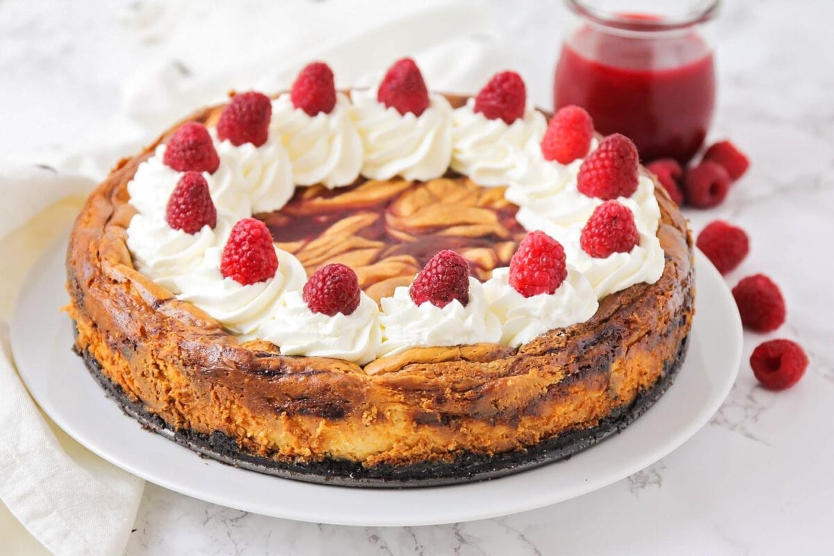 White chocolate raspberry cheesecake on a white plate.