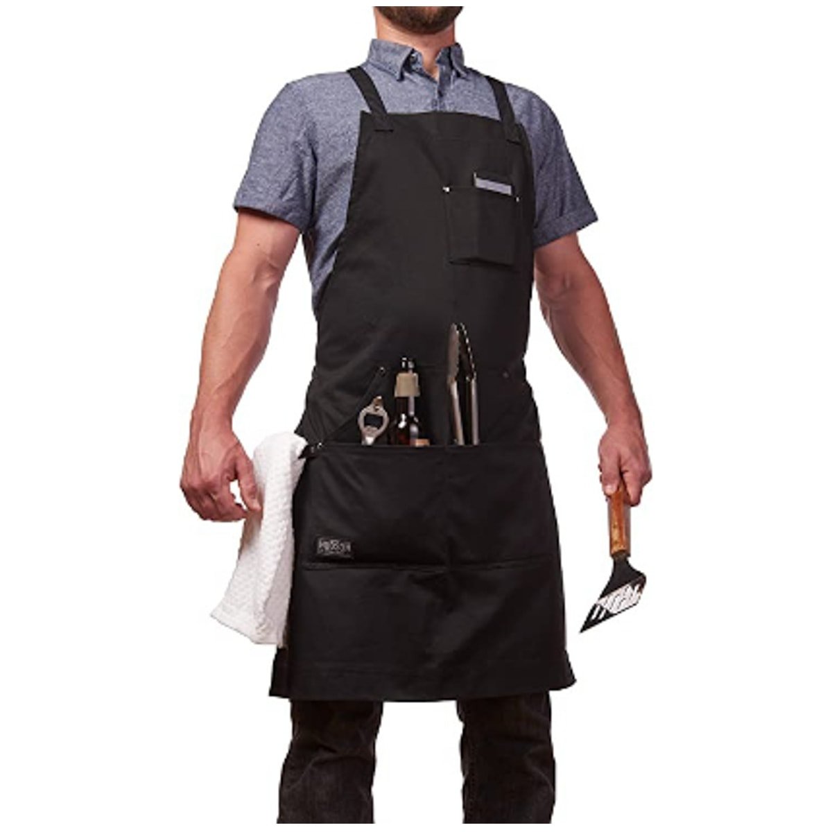 A black apron with several pockets that hold various barbecue tools and supplies displayed on a man.
