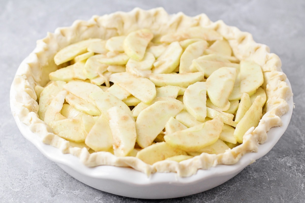 A pie crust filled with apple slices and brown sugar.