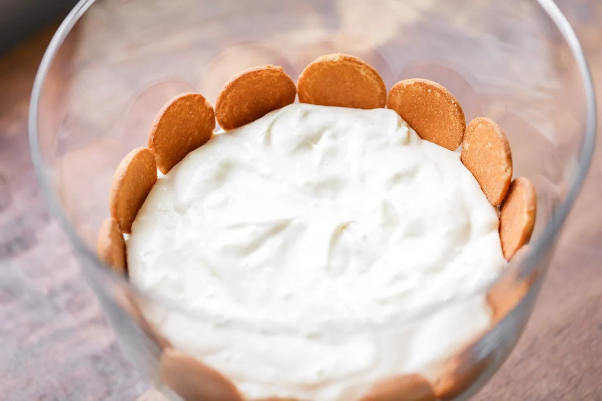 Layering pudding and nilla wafers in a trifle dish.