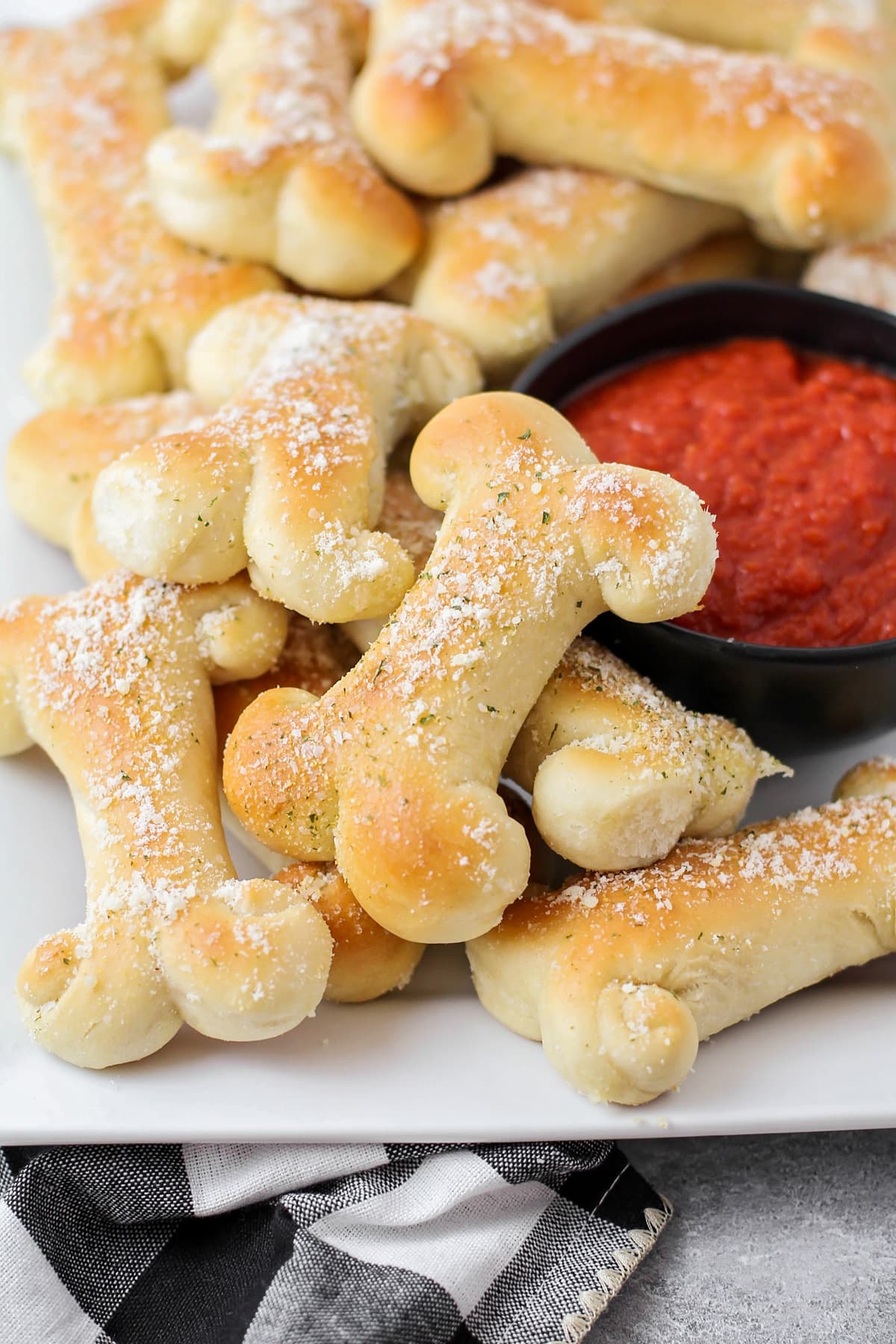 A pile of breadstick bones served with a side of marinara sauce.