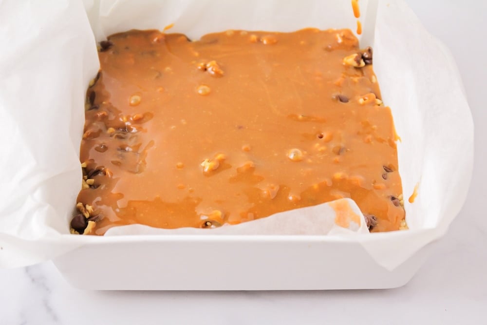 Layering oat bars with caramel and topping.