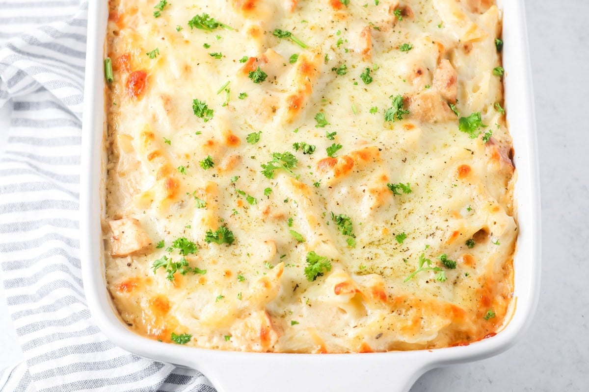 A pan of chicken alfredo bake topped with fresh herbs.