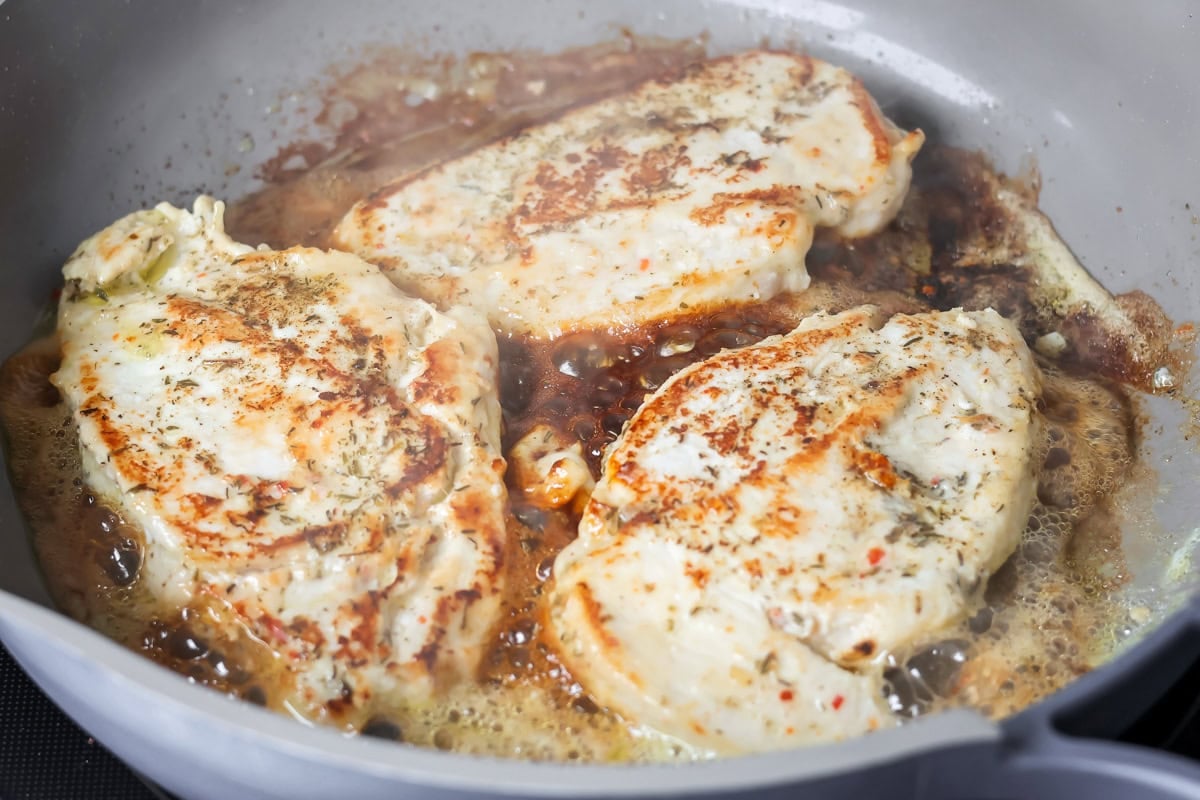 Browning chicken in a skillet for chicken alfredo bake.