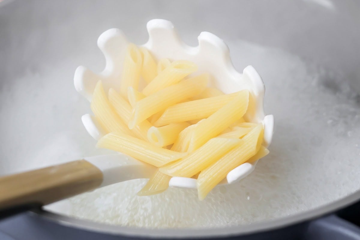 A spoonful of cooked pasta for chicken alfredo bake.