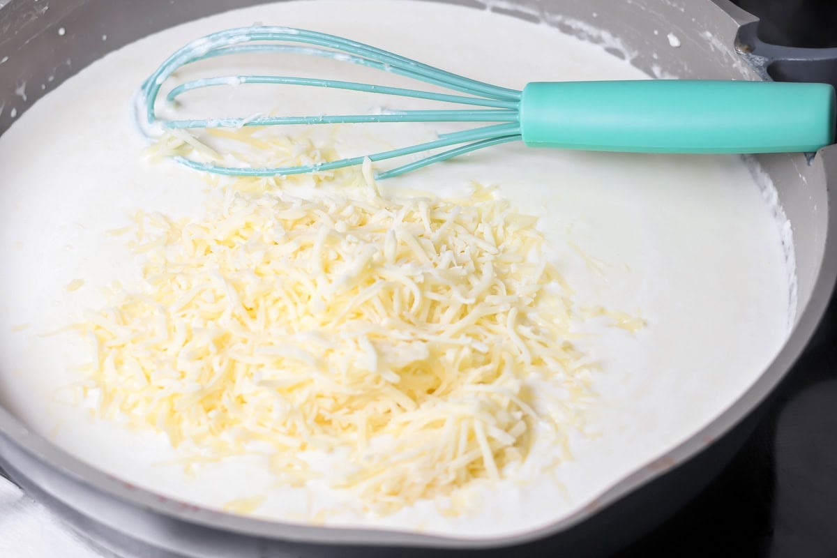 Adding cheese to the sauce for chicken alfredo bake recipe.