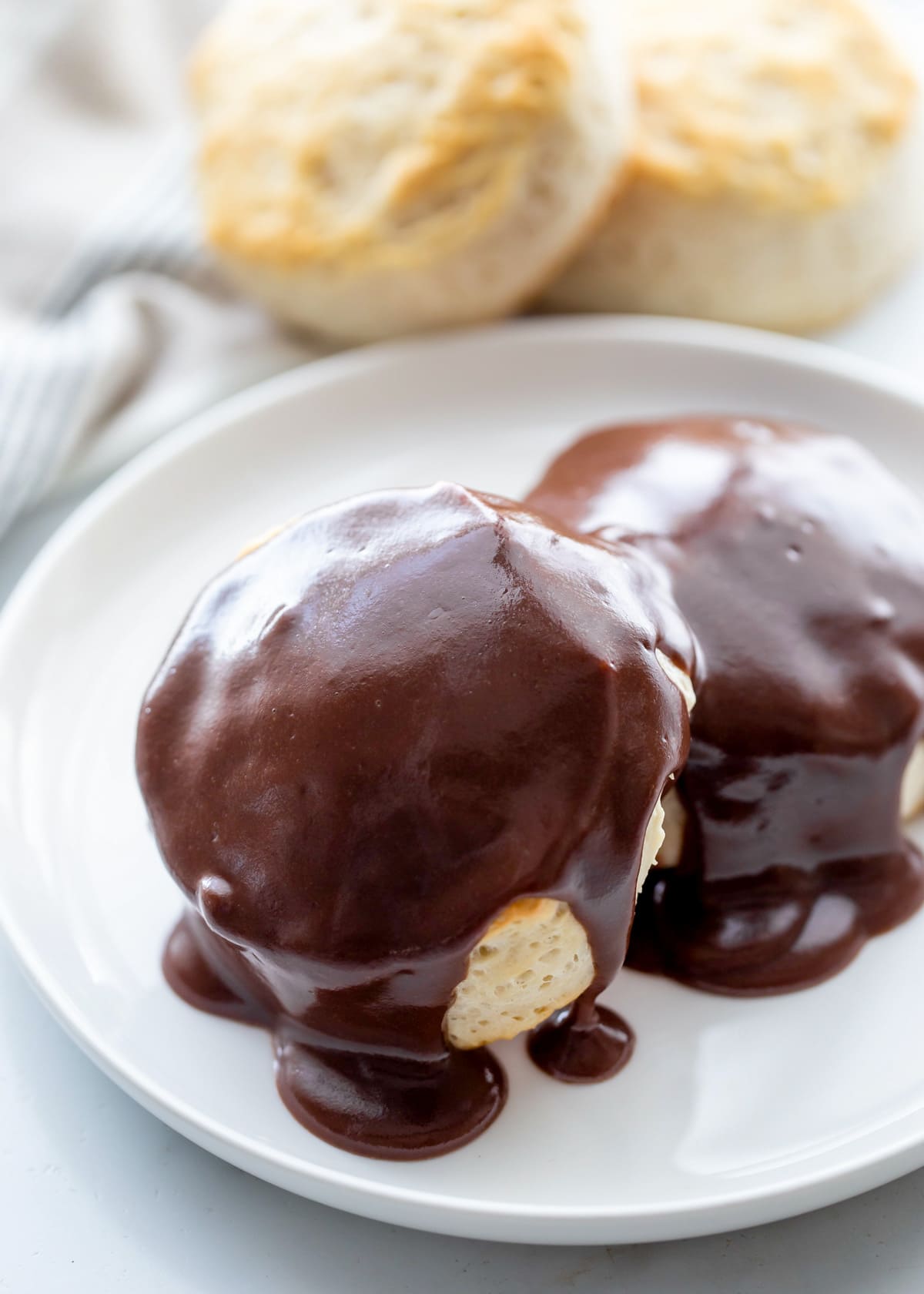 Chocolate gravy served over biscuits on a white plate.