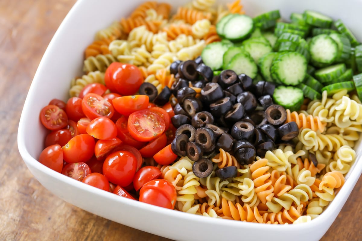 Ingredients for Greek pasta salad in white bowl.