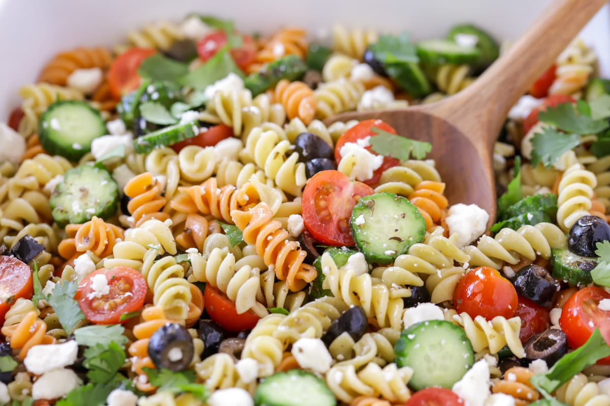 Greek Pasta salad close up image with serving spoon in bowl