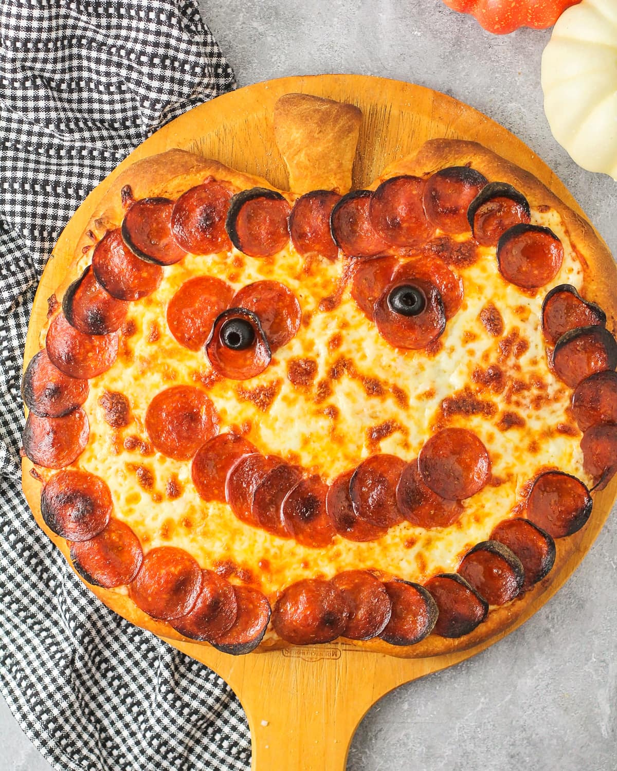 A close up of a halloween pizza shaped like a jack o lantern.