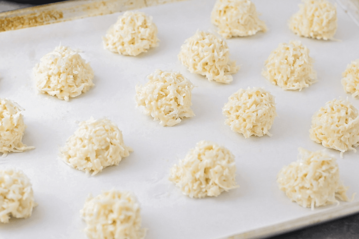 Coconut macaroons scooped onto a lined baking sheet.