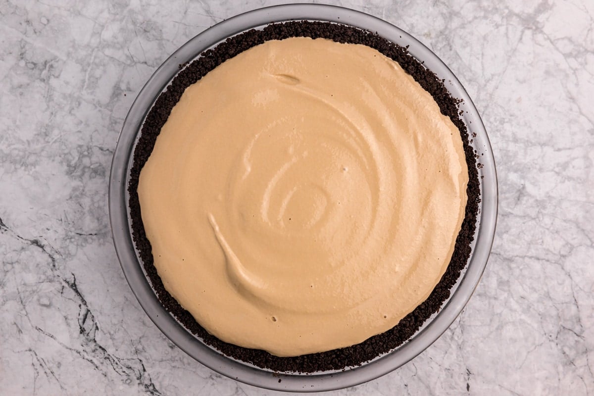 Pouring chocolate pie filling in an oreo crust.
