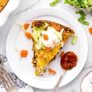 A slice of taco pie served with a spoon of salsa.