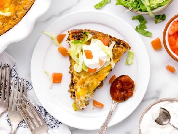 A slice of taco pie served with a spoon of salsa.