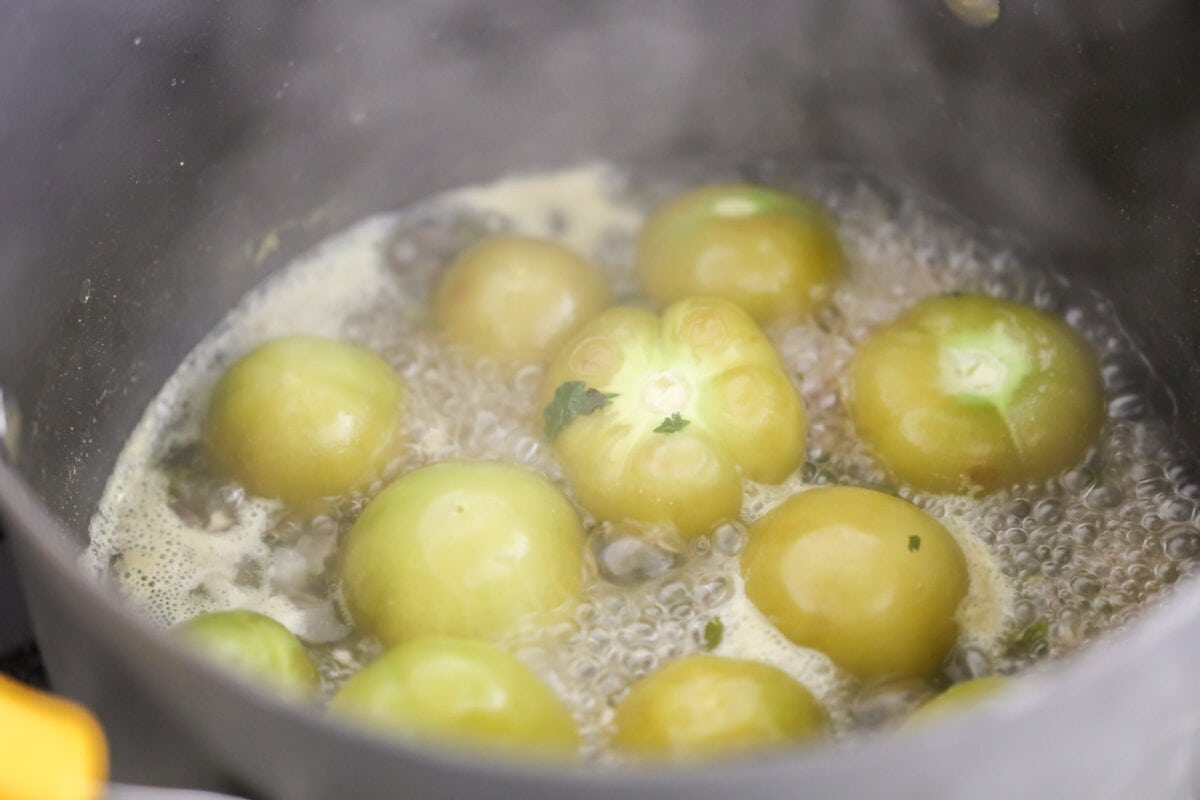 Boiling tomatillos in a pot of water.