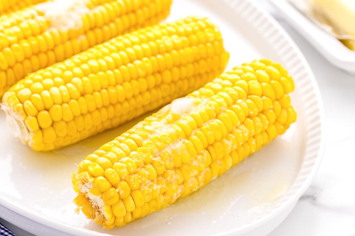 How to boil corn image with cobs on white platter.
