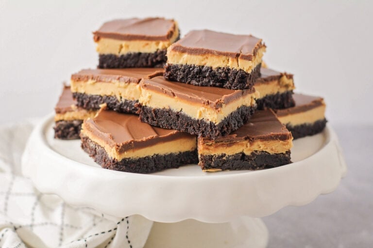 Several buckeye brownies stacked on a white cake platter.